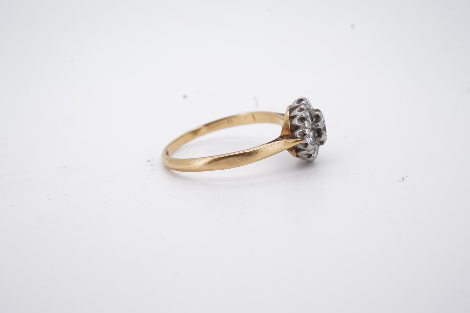 An early 20th century 18ct, plat. and nine stone diamond cluster ring, the central diamond weighing approximately 0.30ct, size Q, gross weight 3.1 grams.